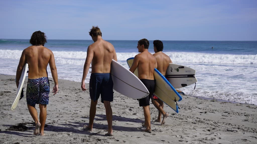 Walking toward the water with surfboards