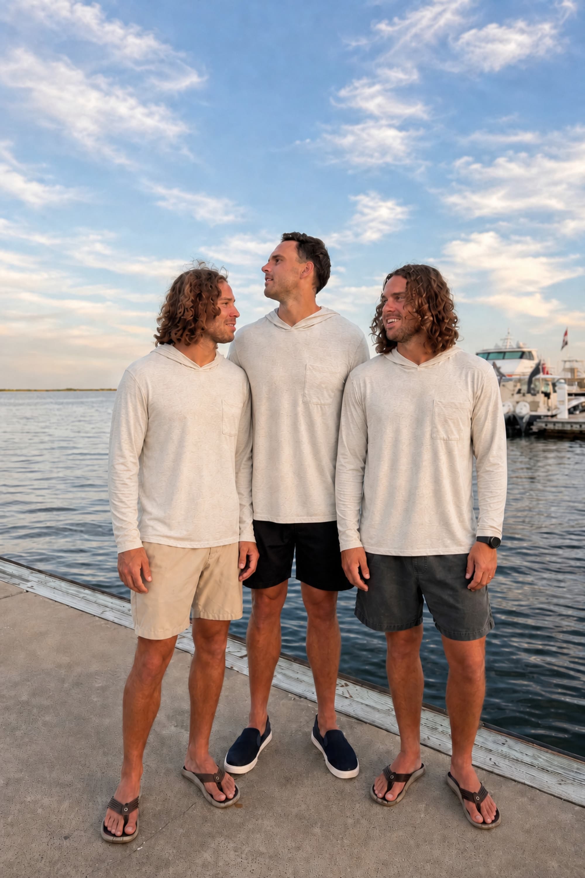 Twin Fin founders on a marina dock wearing the sun hoodie at golden hour